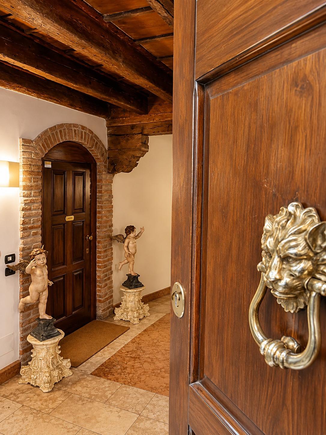 Ingresso indipendente di Marcello Sleep & Spa in Via Lastre 3A, Verona: porta in legno, arco in mattoni e putti barocchi in pietra ai lati